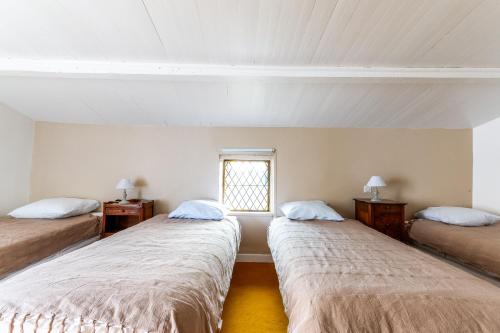 a room with three beds and a window at La Closerie D'Escalin gîte 12 personnes et Jacuzzi in La Garde-Adhémar