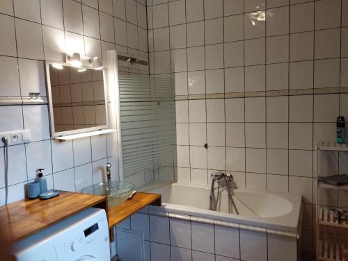 a white tiled bathroom with a tub and a sink at Apartmán v dřevěném domě in Františkovy Lázně