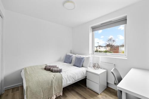 a white bedroom with a bed and a window at 20% OFF Spacious Cosy Home with Free Parking in Exeter