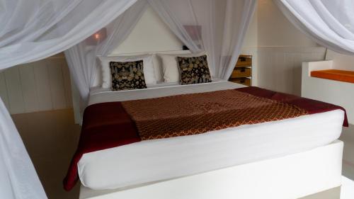 a bedroom with a large white bed with curtains at Anda Amed Villas & Spa in Amed
