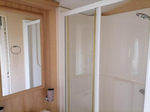 uma casa de banho com um chuveiro e uma porta de vidro em Winchelsea Sands Holiday Park em Winchelsea