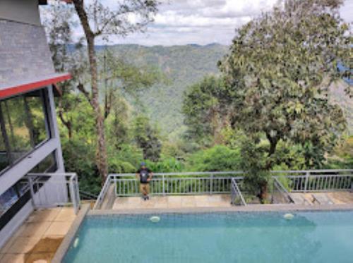 a man standing on a balcony next to a swimming pool at Cliffotel Kerala in Chithragiri