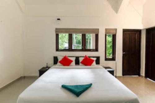 a bedroom with a large bed with red and green pillows at Cliffotel Kerala in Chithragiri