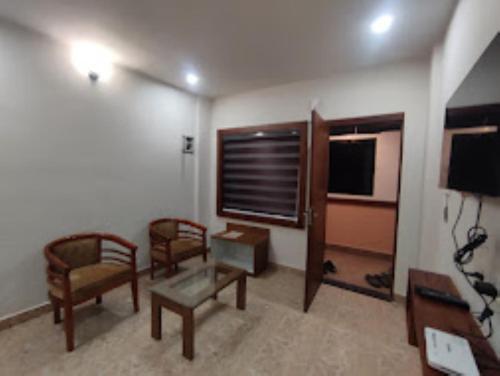 een woonkamer met stoelen en een flatscreen-tv bij Misty Gate Kerala in Vythiri