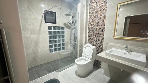 uma casa de banho com um WC, um lavatório e um chuveiro em บ้านโอบอ้อม em That Phanom