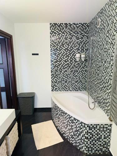 a bath tub in a bathroom with black and white tiles at Villa Vincentów in Myślenice