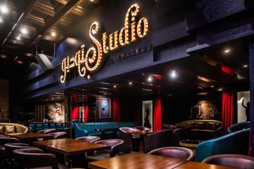 a restaurant with tables and chairs and a neon sign at Capitol Hotel Jumeirah Dubai in Dubai