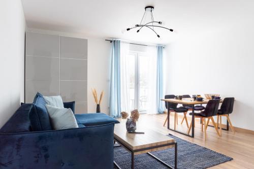 a living room with a blue couch and a table at Apartamenty Sea Colors - Nowoczesne i Komfortowe Apartamenty w Jastrzębiej Górze in Jastrzębia Góra
