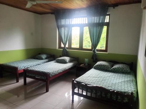 two beds in a room with two windows at Lovely FLowers in Mount Lavinia in Mount Lavinia