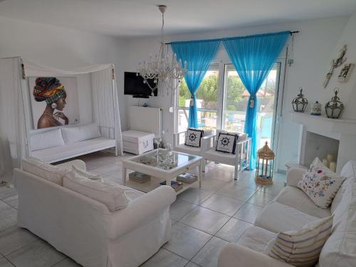 sala de estar con muebles blancos y cortinas azules en OASIS VILLA, en Litóchoron