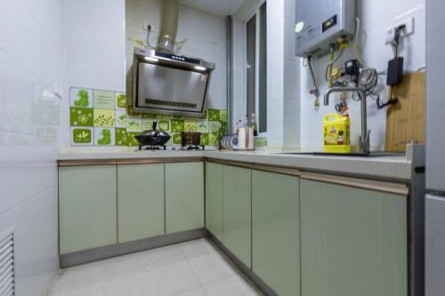 a kitchen with white cabinets and a tv on the wall at Family stay Apartement Livable East City in Huainan