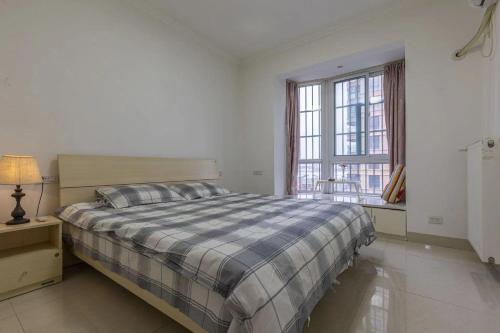 a white bedroom with a bed and a window at Family stay Apartement Livable East City in Huainan
