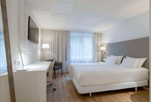 um quarto de hotel com uma grande cama branca e uma secretária em NH Eindhoven Conference Centre Koningshof em Veldhoven