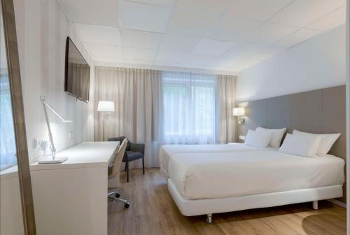 Habitación de hotel con cama blanca grande y escritorio. en NH Eindhoven Conference Centre Koningshof, en Veldhoven