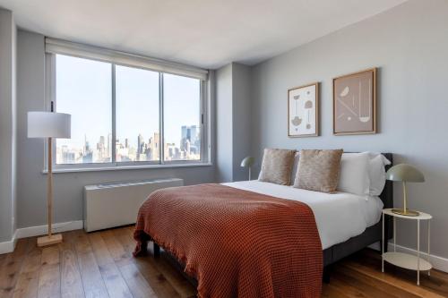 um quarto com uma cama e uma grande janela em Midtown West 2br w gym roofdeck nr Hudson NYC-1395 em Nova York