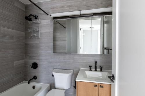 uma casa de banho com um lavatório, um WC e um espelho. em Midtown West 2br w gym roofdeck nr Hudson NYC-1395 em Nova York