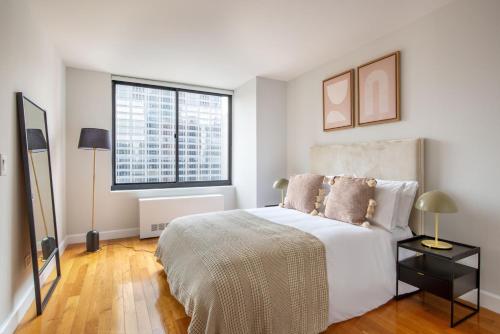 a white bedroom with a large bed and a window at Midtown 1br w gym elevator nr Rockefeller Ctr NYC-1401 in New York