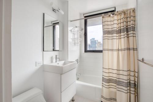 a white bathroom with a sink and a shower at Midtown 1br w gym elevator nr Rockefeller Ctr NYC-1401 in New York