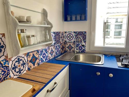 cocina con azulejos azules y blancos y fregadero en Cuore d’Orlando apartment, en Capo dʼOrlando