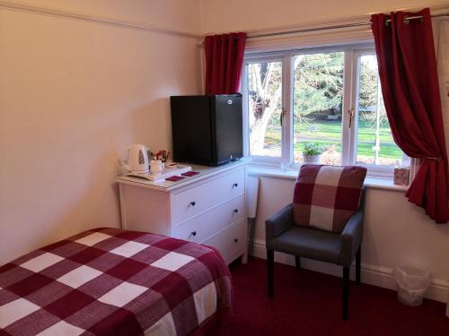 1 dormitorio con 1 cama, TV y silla en Ashgrove House en Stratford-upon-Avon