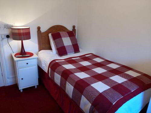 a bedroom with a bed and a lamp on a night stand at Ashgrove House in Stratford-upon-Avon