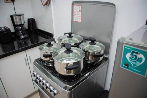 vier potten en pannen op een fornuis in een keuken bij GWETH STUDIO APARTMENT in Nairobi