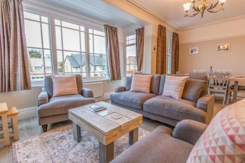 a living room with couches and a table at Sully's Cove, stylish apartment near Southwold Pier in Southwold