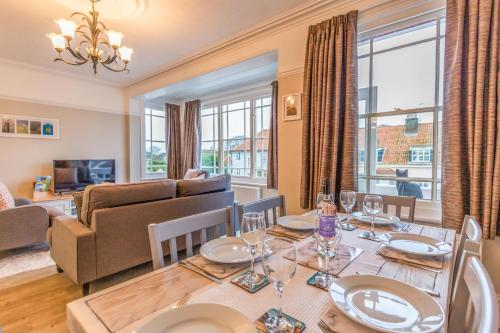 a dining room with a table and a living room at Sully's Cove, stylish apartment near Southwold Pier in Southwold