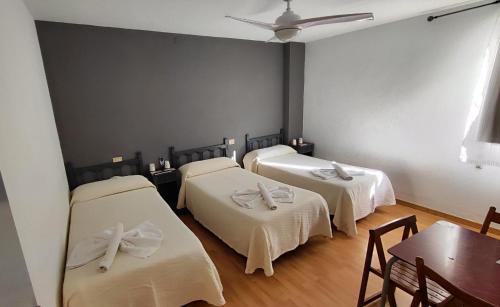 a room with three beds with white sheets and a table at Hello Villarreal Pension in Villareal