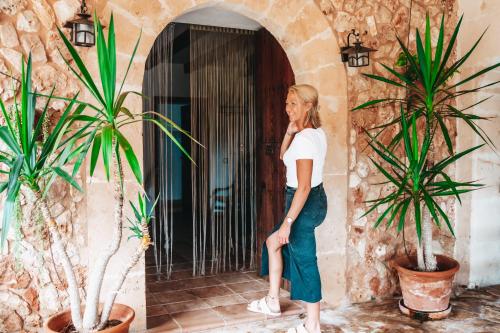 una mujer parada frente a una puerta con dos plantas en Agroturisme Son Barceló Mas, en Campos