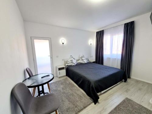 a bedroom with a bed and a table and a chair at Vila Giulia Voineasa in Voineasa
