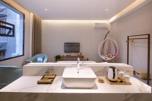 a bathroom with a white sink and a television at 云隐兮江景民宿 in Fenghuang