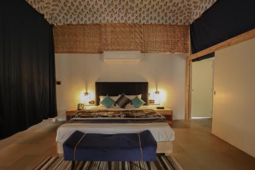 a bedroom with a large bed with a blue chair at Aranya by Stories in Jaipur