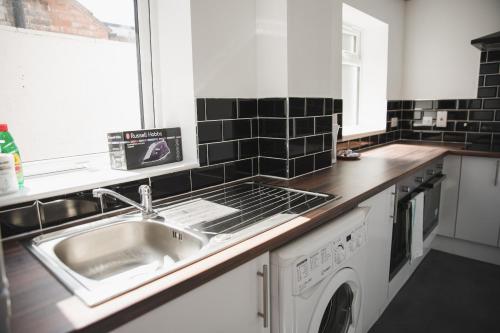 a kitchen with a sink and a washing machine at Leicester Park House in Leicester
