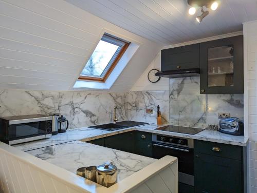 a kitchen with green cabinets and a window at Morrigan 7-Hot Tub-Pet Friendly-Boutique-Perthshire-Families in Perth