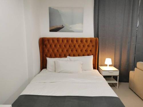 a bed with a orange headboard in a bedroom at Lovely spacious studio with new branded furniture in Dubai