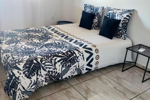 a bedroom with a bed with a black and white comforter at Les lataniers 1 - Vue sur mer in Saint-Pierre