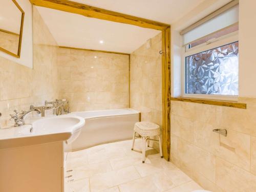 a bathroom with a tub and a sink and a window at 3 Bed in Chulmleigh 87779 in Eggesford
