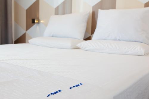a bed with white sheets and pillows with blue writing on it at Perla Luxury in Ulcinj