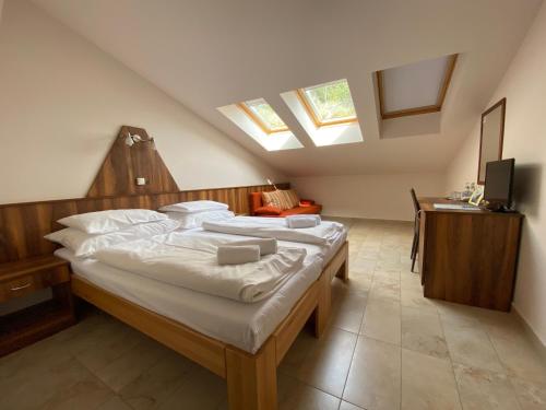 1 dormitorio con 1 cama grande con almohadas blancas en Sástó Hotel, en Mátrafüred