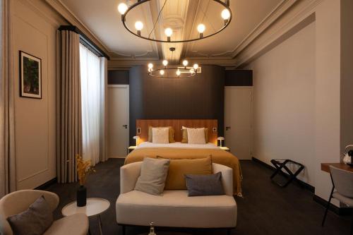 1 dormitorio con cama, sofá y lámpara de araña en Hotel Kint en Valkenburg