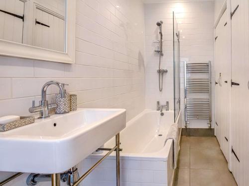 uma casa de banho branca com um lavatório e uma banheira em 2 Bed in Tenby 88608 em Tenby
