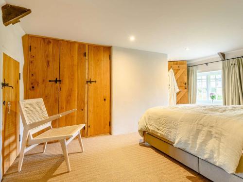 a bedroom with a bed and a chair and a window at 3 Bed in Beaminster 87914 in South Perrott