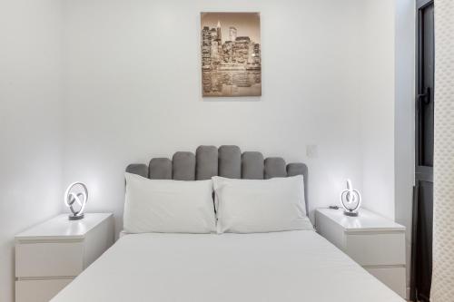 - une chambre blanche avec un grand lit et 2 tables de chevet dans l'établissement Studio Parisien proche Tour Eiffel - 3 min métro, à Paris