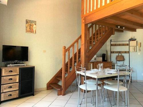 une salle à manger avec une table, des chaises et un escalier dans l'établissement La Palmyre - APPARTEMENT au cœur du centre - résidence AGATHEA - BALCON, aux Mathes