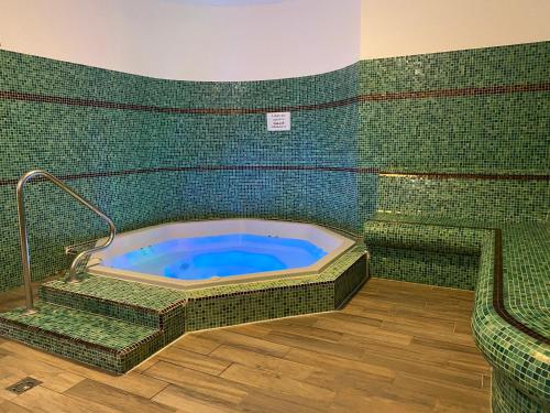 uma banheira de hidromassagem numa sala com azulejos verdes em Sástó Hotel em Matrafured