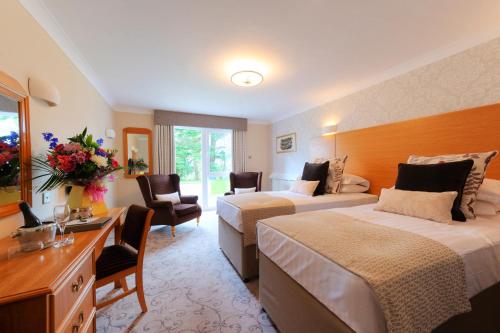 a hotel room with two beds and a desk at Appleby Manor Hotel & Garden Spa in Appleby
