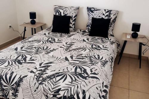 a black and white bed with two pillows on it at Les lataniers 2 - Vue sur mer in Saint-Pierre