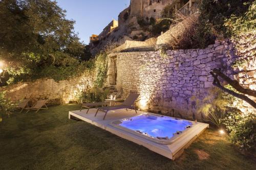 a hot tub in a yard next to a stone wall at Locanda Don Serafino Historical Boutique Hotel in Ragusa