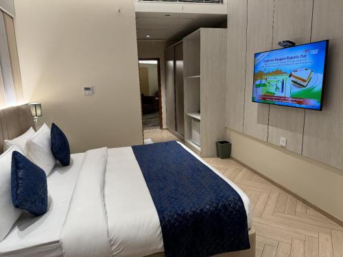 Chinmay Hotel & Resort في لاكناو: غرفة نوم مع سرير وتلفزيون على الحائط